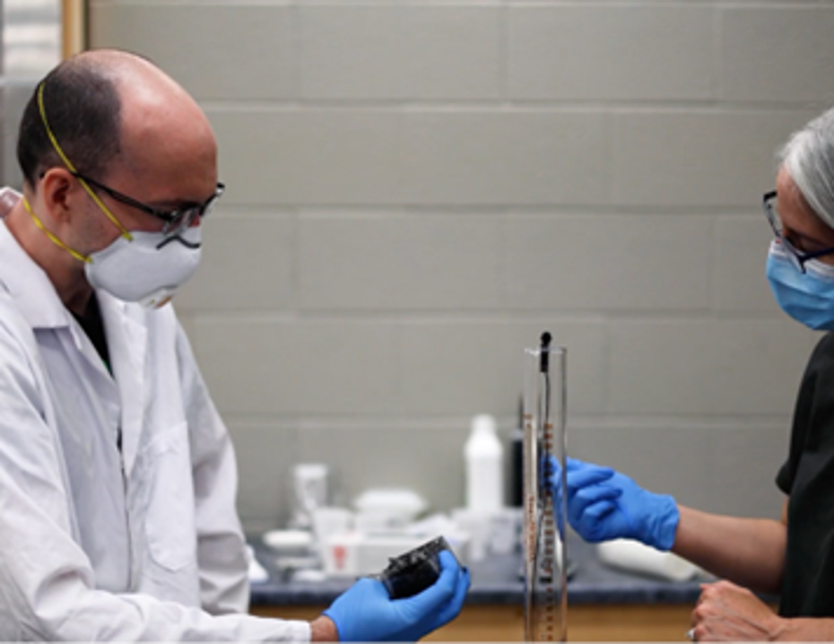 Two scientists wear PPE in a lab setting